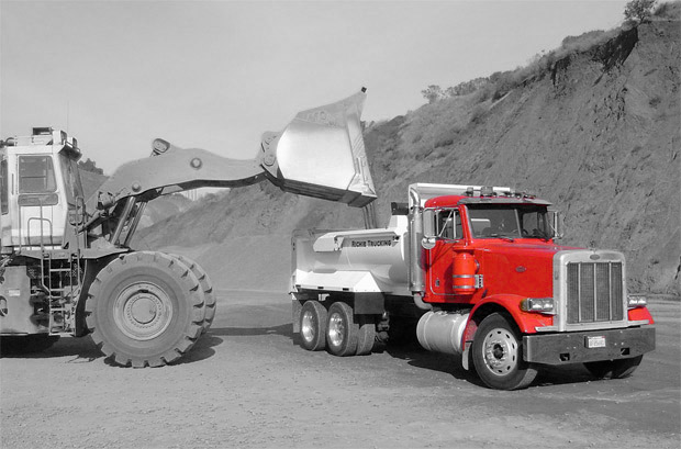 a construction site tractor loading a dump truck with dirt